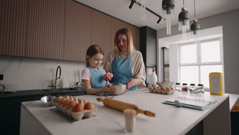 mom-and-little-daughter-are-cooking-together-and-having-fun-in-home-kitchen-mother-is-teaching-her-child-to-cook-cake